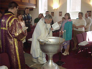 Father Andrew prepares the Baptismal Font.