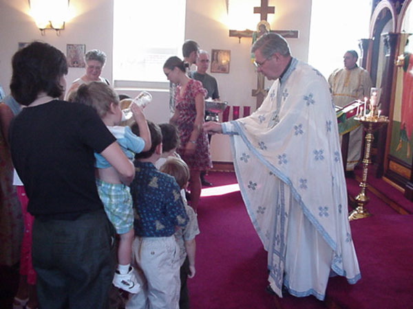 Father Andrew blesses the children with Holy Water.