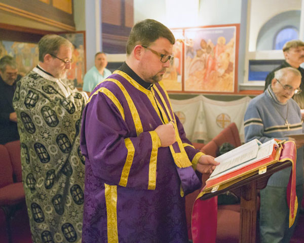 Father Paul reading of the Passion Gospels .